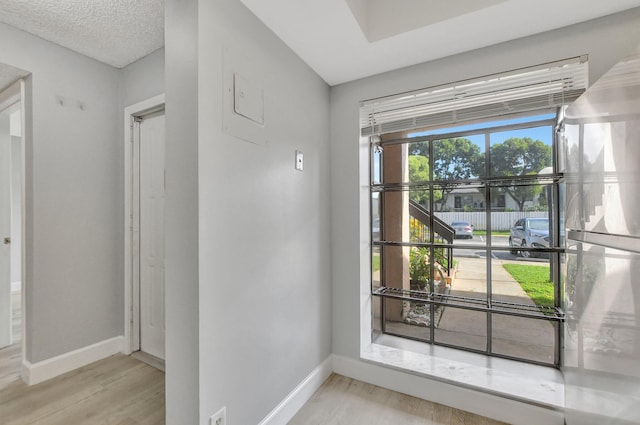 doorway to outside featuring a textured ceiling and light hardwood / wood-style floors