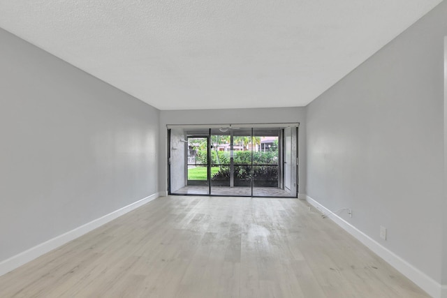 empty room featuring light wood-type flooring and a textured ceiling