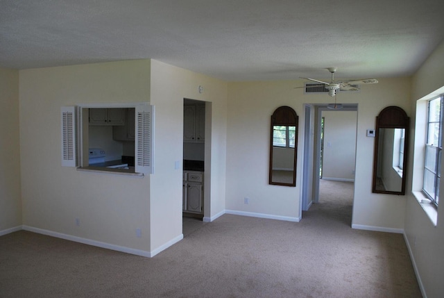 carpeted empty room featuring ceiling fan, plenty of natural light, and a textured ceiling