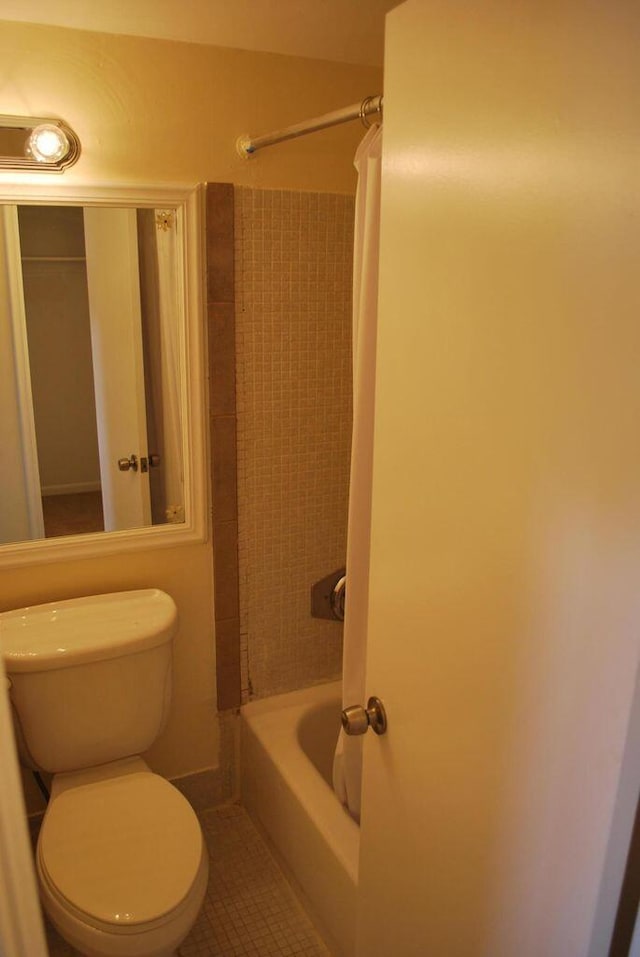 bathroom featuring tile patterned flooring, toilet, and shower / tub combo with curtain