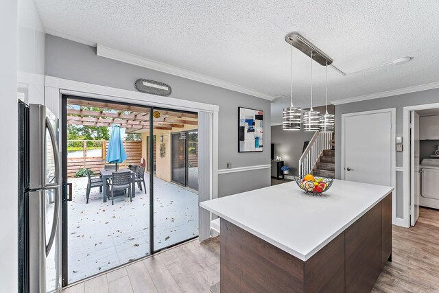 411 4th Ter, Palm Beach Gardens, FL 33418 - kitchen featuring freestanding refrigerator, light wood-type flooring, crown molding, a kitchen island, and light countertops