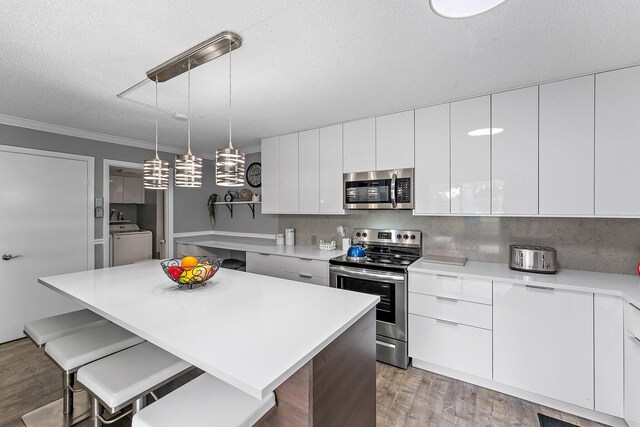 411 4th Ter, Palm Beach Gardens, FL 33418 - kitchen with appliances with stainless steel finishes, modern cabinets, a textured ceiling, light wood-style floors, and a breakfast bar