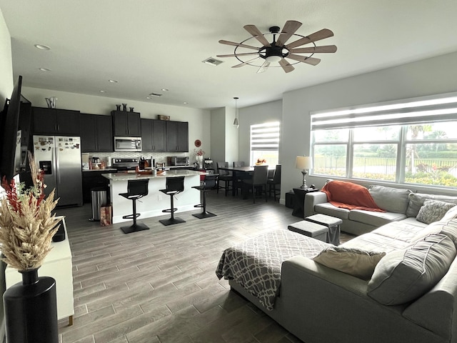 living room with light wood-type flooring, sink, and ceiling fan