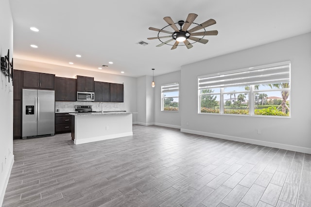 kitchen featuring appliances with stainless steel finishes, pendant lighting, a kitchen island, and light hardwood / wood-style flooring