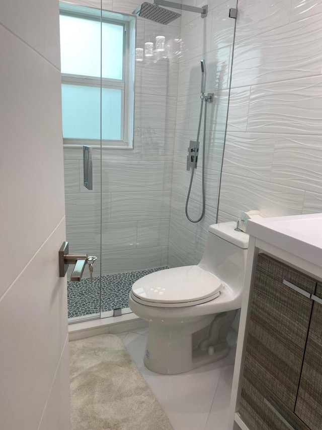 bathroom featuring tile walls, tile patterned flooring, a shower with shower door, vanity, and toilet