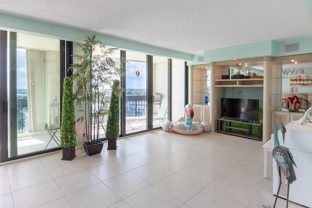 unfurnished living room with a textured ceiling, floor to ceiling windows, and light tile patterned floors