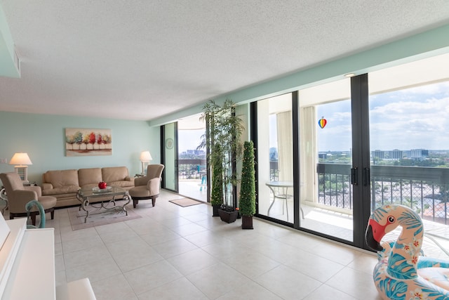 living room with a textured ceiling, a wall of windows, and light tile patterned flooring