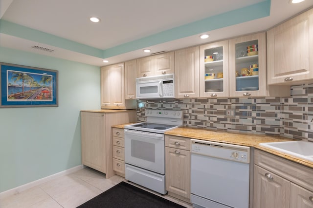 kitchen featuring light brown cabinets, light tile patterned flooring, tasteful backsplash, and white appliances