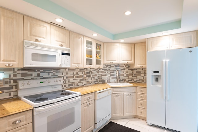 kitchen featuring white appliances, sink, light tile patterned floors, and light brown cabinets