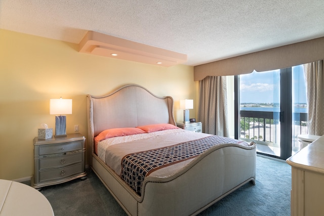 carpeted bedroom with a water view, a textured ceiling, and access to outside