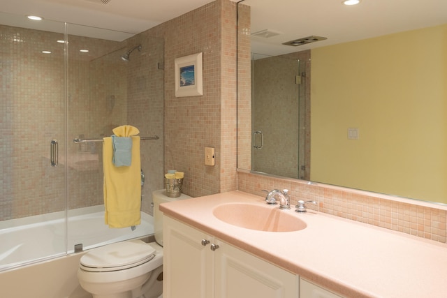 full bathroom featuring vanity, toilet, tasteful backsplash, and combined bath / shower with glass door