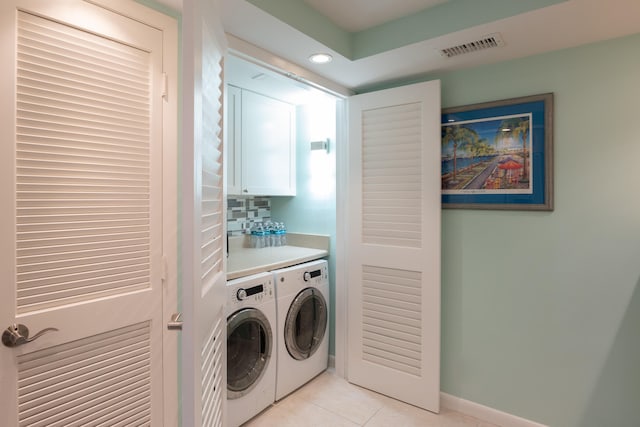 laundry room featuring washing machine and clothes dryer, indoor bar, cabinets, and light tile patterned floors