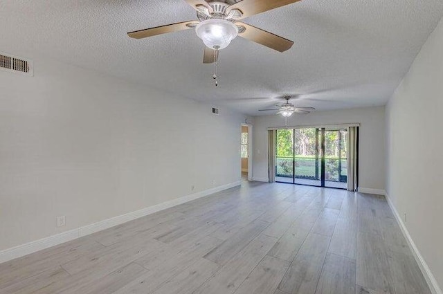 empty room with a textured ceiling, light hardwood / wood-style floors, and ceiling fan