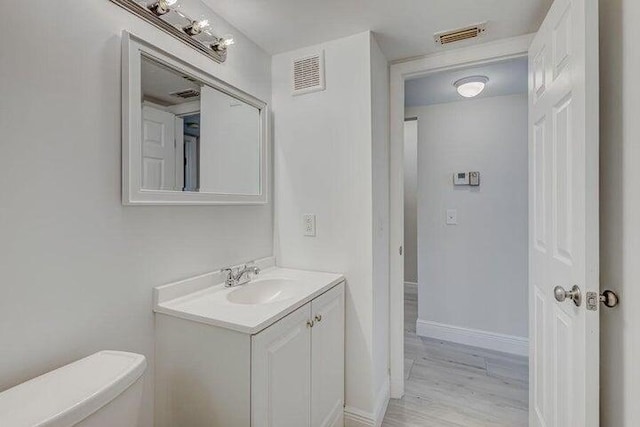 bathroom featuring wood-type flooring, vanity, and toilet