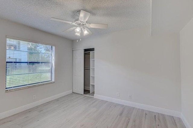 unfurnished bedroom featuring ceiling fan, a textured ceiling, light wood-type flooring, and a closet