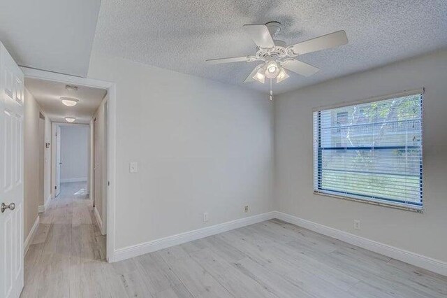 unfurnished room featuring light wood-type flooring, a textured ceiling, and a healthy amount of sunlight