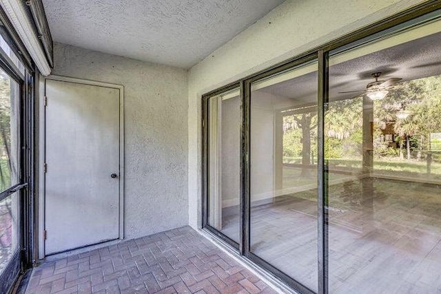 unfurnished sunroom featuring ceiling fan