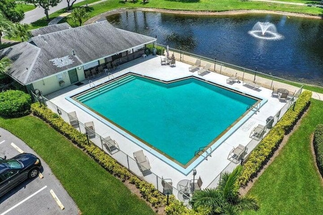 view of pool featuring a lawn, a water view, and a patio area