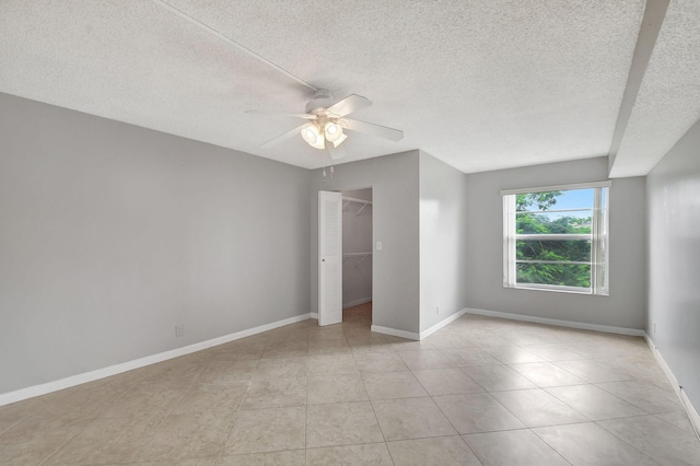 unfurnished bedroom featuring a spacious closet, a textured ceiling, ceiling fan, and a closet