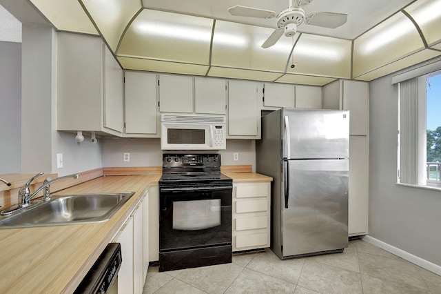 kitchen featuring light tile patterned floors, sink, stainless steel fridge, ceiling fan, and black range with electric cooktop