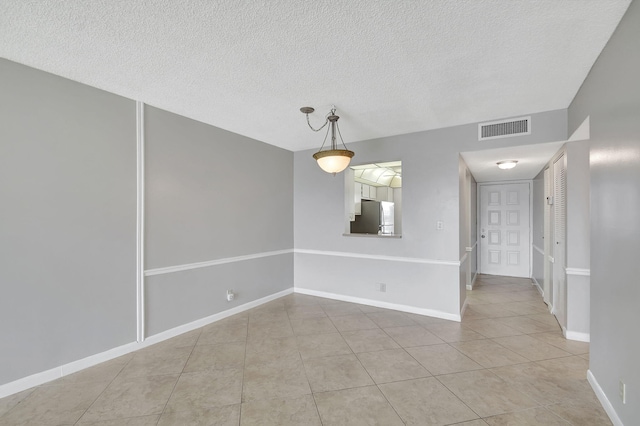 spare room with light tile patterned floors and a textured ceiling