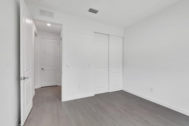 unfurnished bedroom featuring a closet and dark wood-type flooring