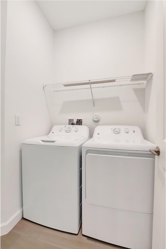 washroom with light hardwood / wood-style floors and washing machine and dryer