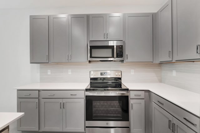 kitchen with stainless steel appliances, decorative backsplash, and gray cabinetry