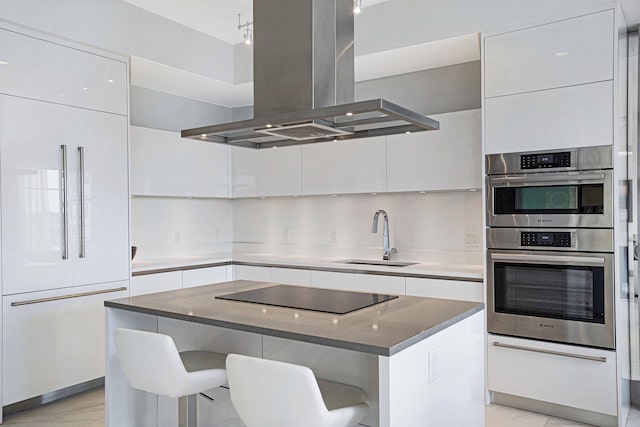 kitchen with sink, white cabinetry, island range hood, a kitchen island, and a kitchen breakfast bar