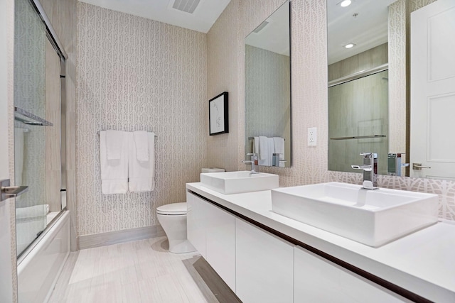 full bathroom featuring combined bath / shower with glass door, vanity, and toilet