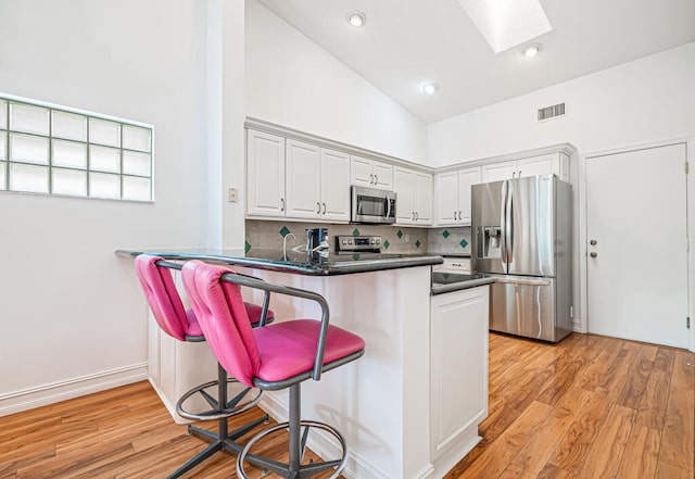 kitchen featuring white cabinetry, high vaulted ceiling, stainless steel appliances, and kitchen peninsula