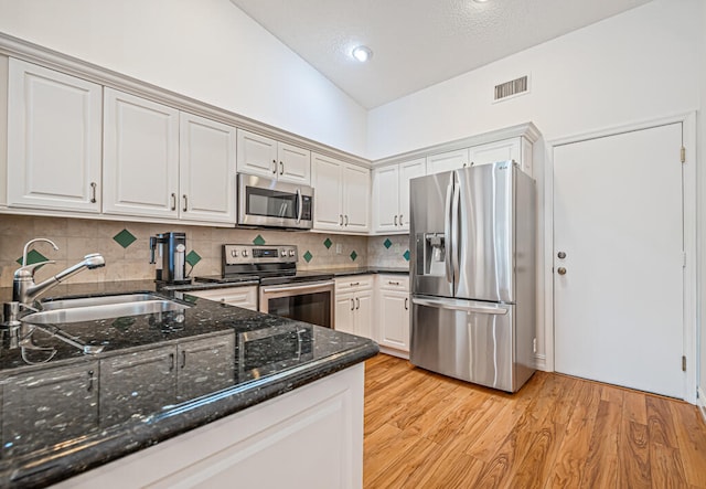 kitchen featuring white cabinets, stainless steel appliances, sink, and backsplash