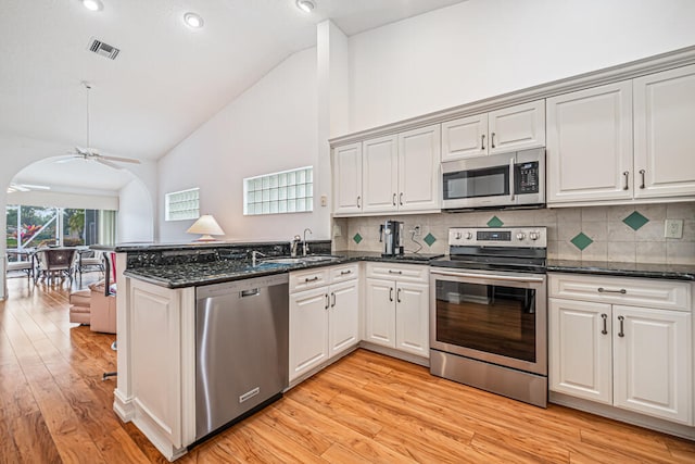 kitchen with kitchen peninsula, ceiling fan, stainless steel appliances, decorative backsplash, and light hardwood / wood-style flooring