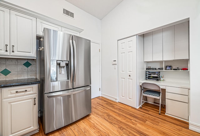 kitchen featuring built in desk, stainless steel fridge, light hardwood / wood-style floors, and tasteful backsplash