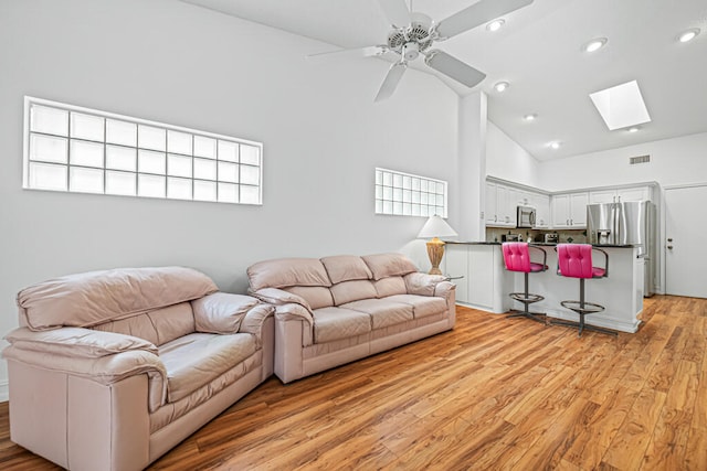 living room with plenty of natural light, high vaulted ceiling, light hardwood / wood-style floors, and ceiling fan