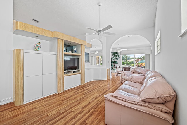 living room with a textured ceiling, wood-type flooring, and ceiling fan