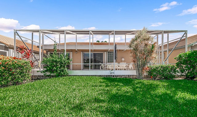 back of property with glass enclosure and a lawn