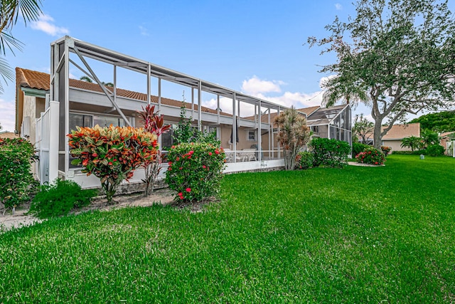 rear view of property with a lawn and glass enclosure