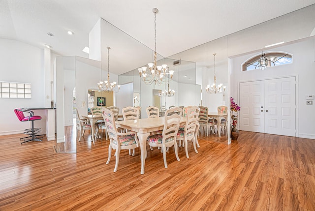 dining room featuring a chandelier, high vaulted ceiling, and light wood-type flooring