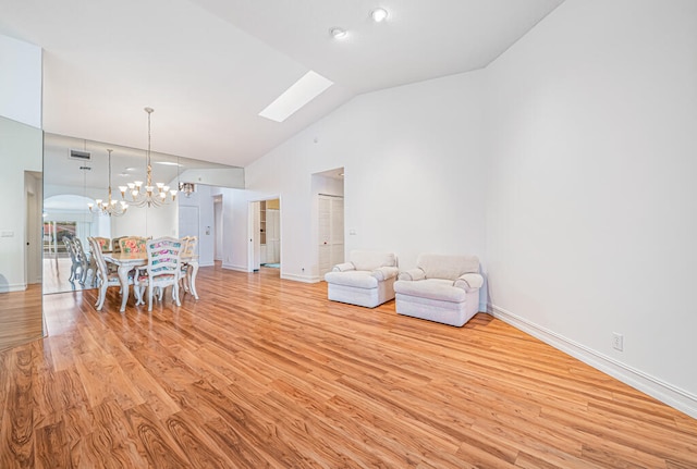 unfurnished room featuring an inviting chandelier, light hardwood / wood-style flooring, high vaulted ceiling, and a skylight