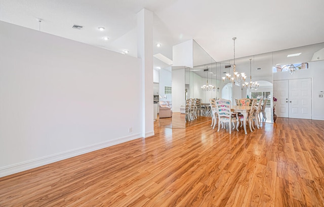 unfurnished dining area featuring a notable chandelier, a high ceiling, and light wood-type flooring