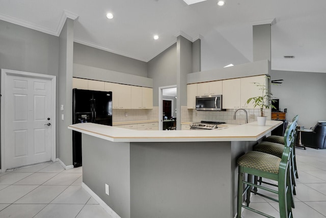 kitchen featuring backsplash, a kitchen breakfast bar, light tile patterned floors, kitchen peninsula, and stainless steel appliances