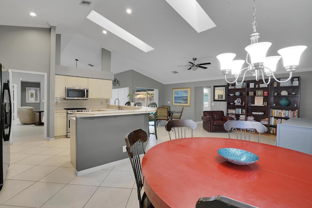 dining area featuring light tile patterned flooring, crown molding, a skylight, high vaulted ceiling, and ceiling fan with notable chandelier