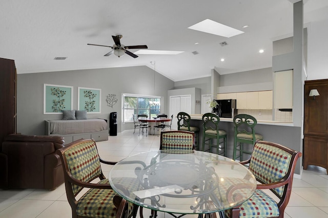 tiled dining area featuring ceiling fan and vaulted ceiling with skylight