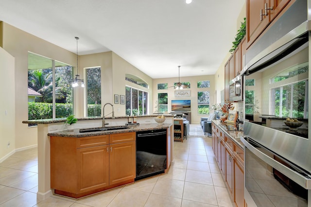 kitchen with pendant lighting, black dishwasher, light stone countertops, and sink