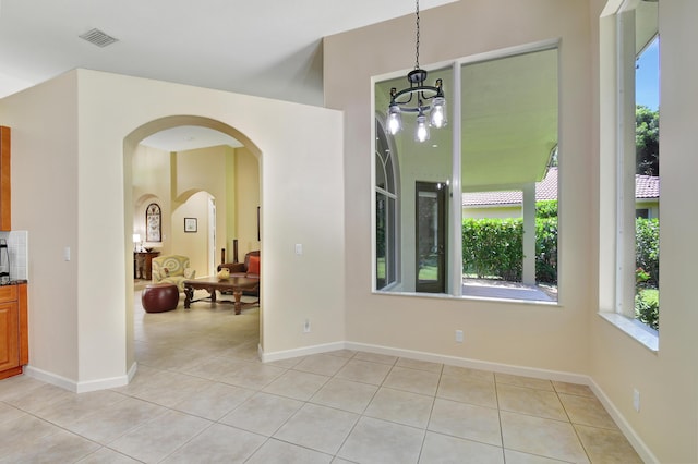 interior space with light tile patterned floors and an inviting chandelier