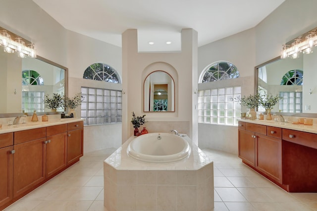 bathroom with tile patterned floors, vanity, and a relaxing tiled tub