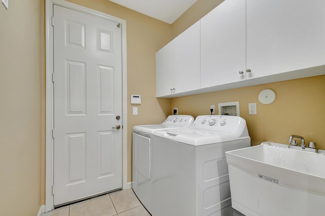 clothes washing area with independent washer and dryer, cabinets, light tile patterned floors, and sink