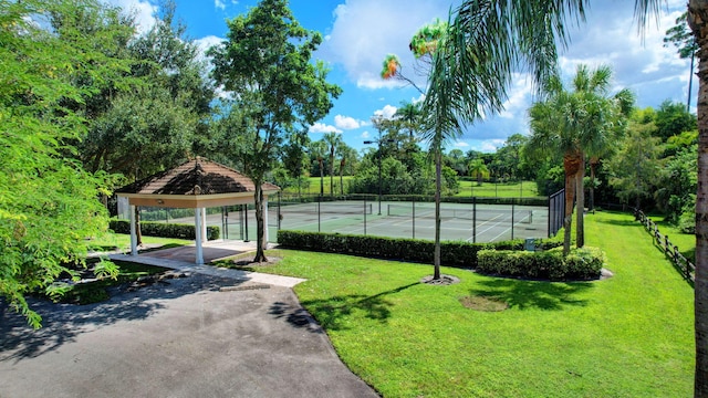 view of property's community with a lawn and tennis court