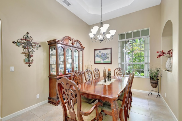 tiled dining room with a raised ceiling, plenty of natural light, and a notable chandelier